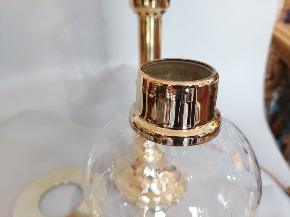 A pair of turned brass table lamps with stepped circular bases, cylindrical stems, and clear flared glass storm shades. View X