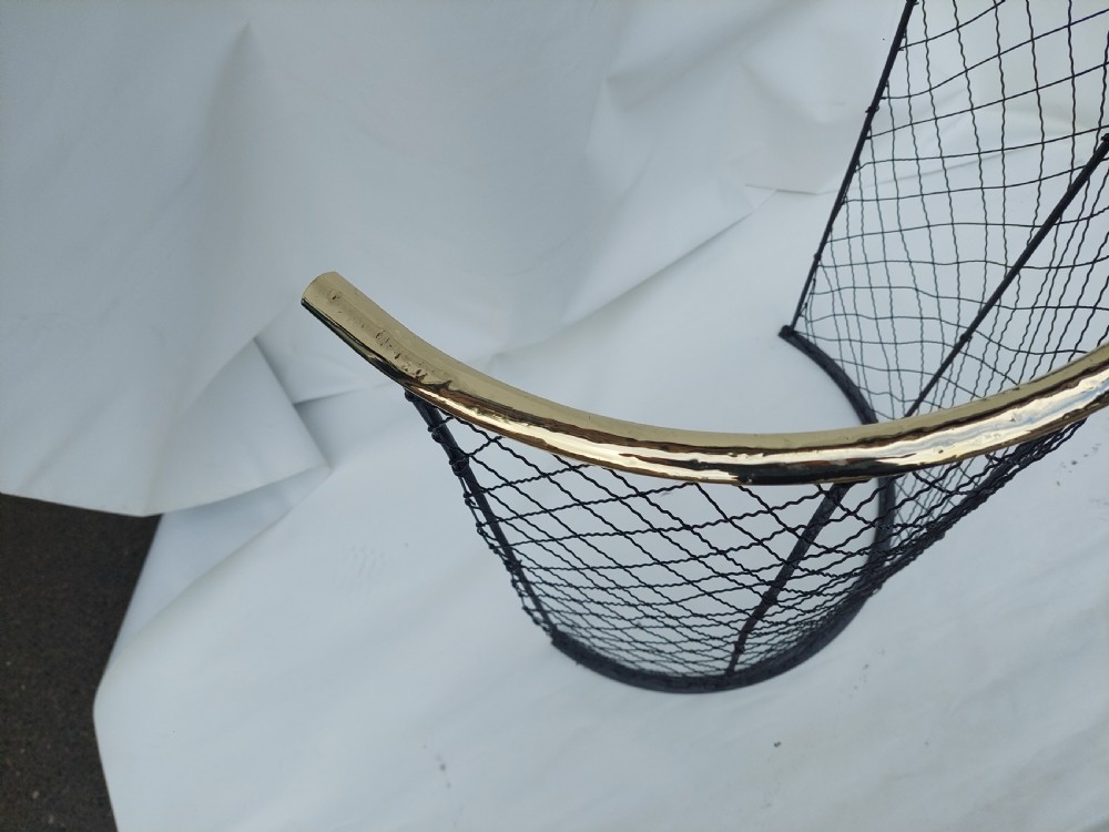 A tall, curved Victorian nursery fender constructed from black wire mesh with vertical iron supports and a polished brass top rail. View IV