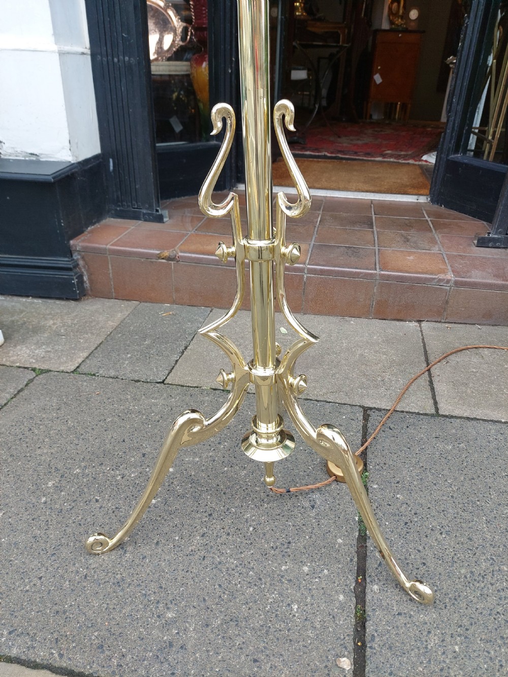 An early 20th-century Art Nouveau polished brass adjustable standard lamp featuring a tripod base with whiplash curves and three arms holding pink fluted glass shades. View III