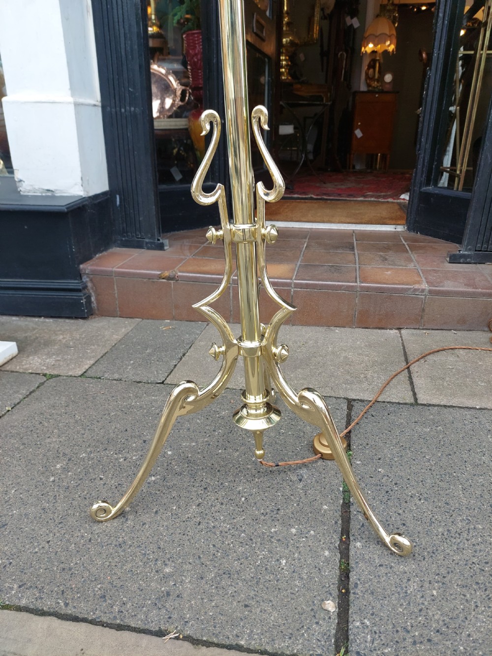 An early 20th-century Art Nouveau polished brass adjustable standard lamp featuring a tripod base with whiplash curves and three arms holding pink fluted glass shades. View IV
