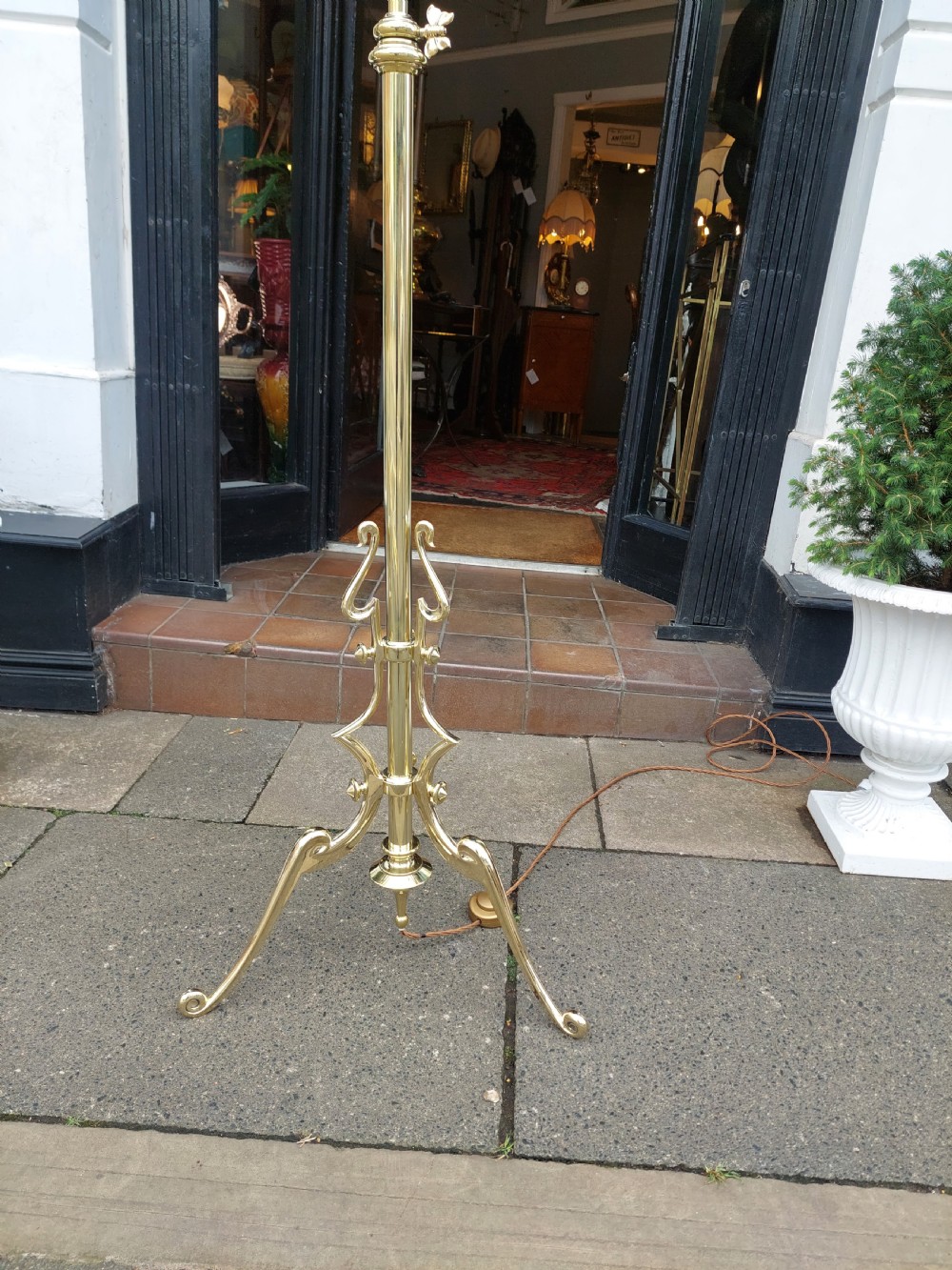 An early 20th-century Art Nouveau polished brass adjustable standard lamp featuring a tripod base with whiplash curves and three arms holding pink fluted glass shades. View V