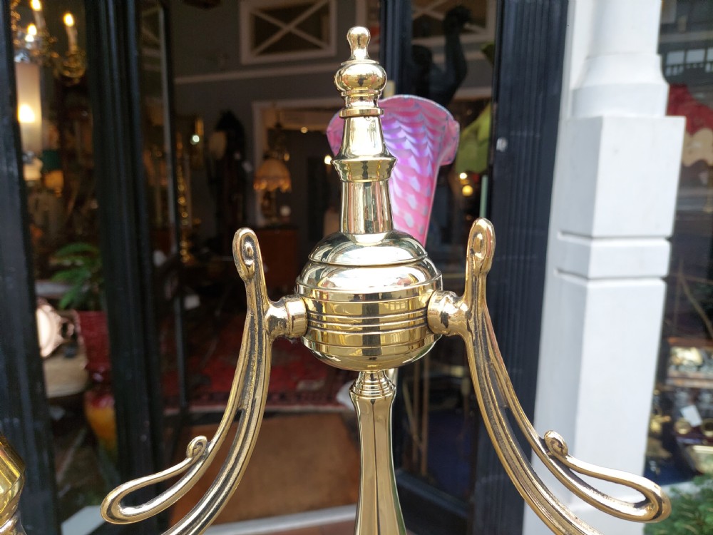 An early 20th-century Art Nouveau polished brass adjustable standard lamp featuring a tripod base with whiplash curves and three arms holding pink fluted glass shades. View VIII
