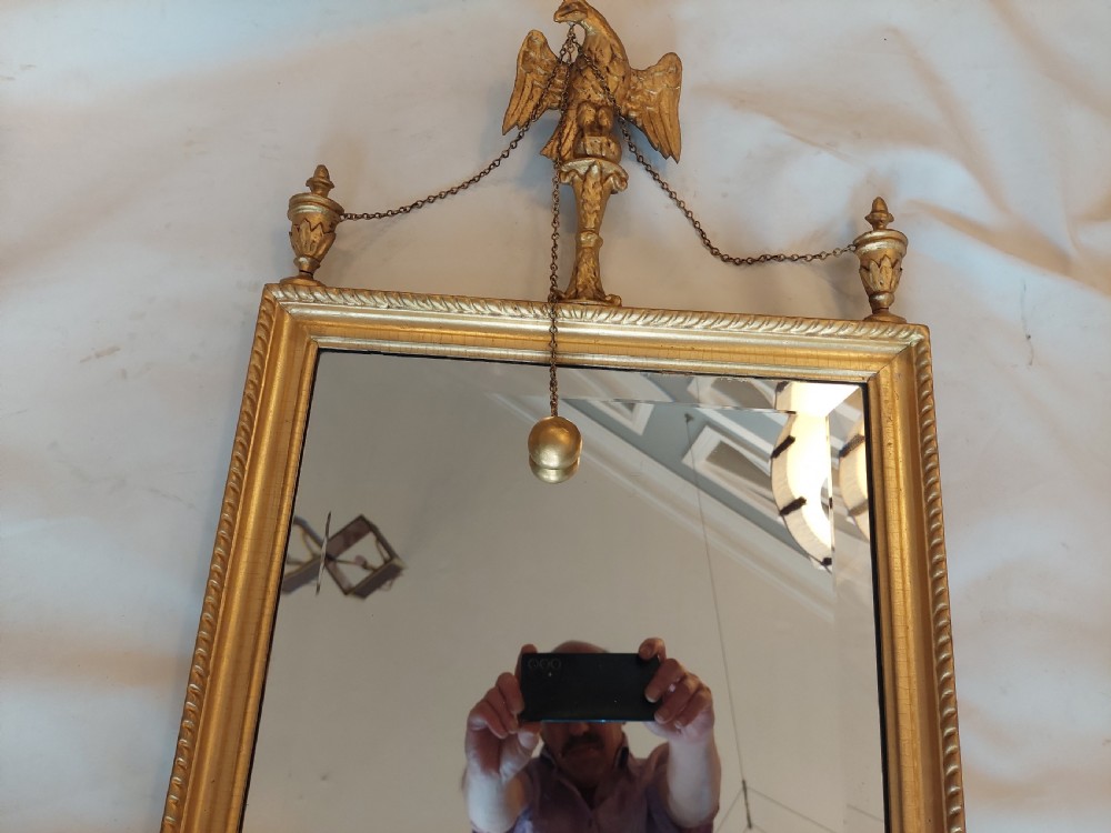 A tall rectangular George III giltwood pier mirror featuring an eagle surmounting a central crest with delicate hanging chains and flanking corner finials. View VI