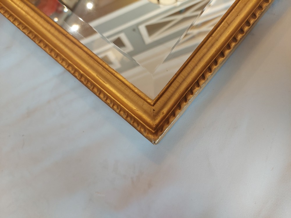 A tall rectangular George III giltwood pier mirror featuring an eagle surmounting a central crest with delicate hanging chains and flanking corner finials. View VII