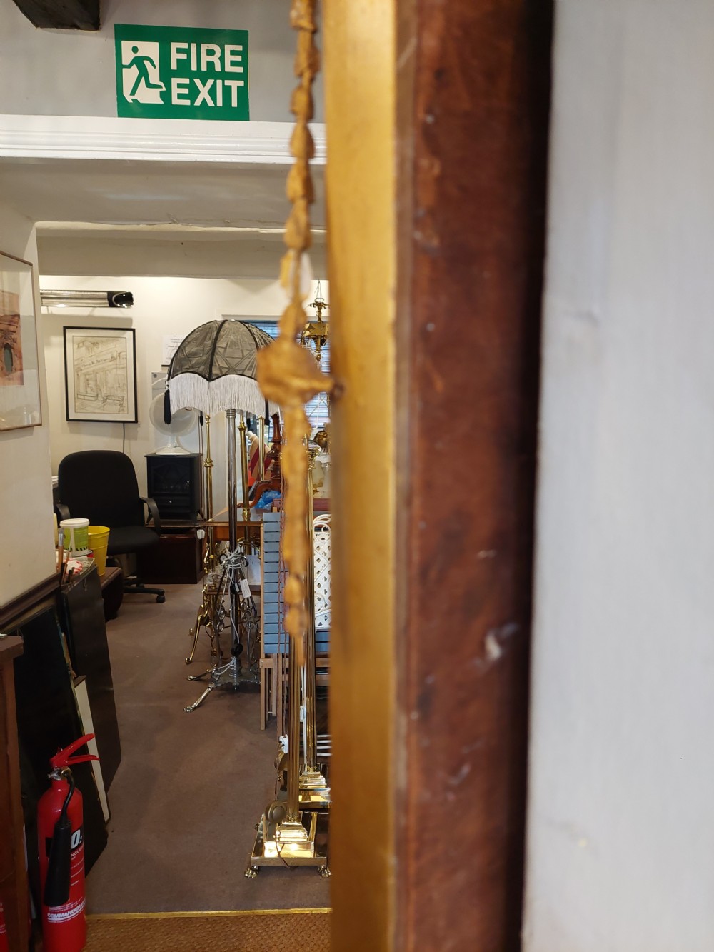 A late 19th-century Adam Revival gilt-gesso wall mirror featuring an urn and garland cresting, beaded frame moulding, and bevelled mirror plates. View X