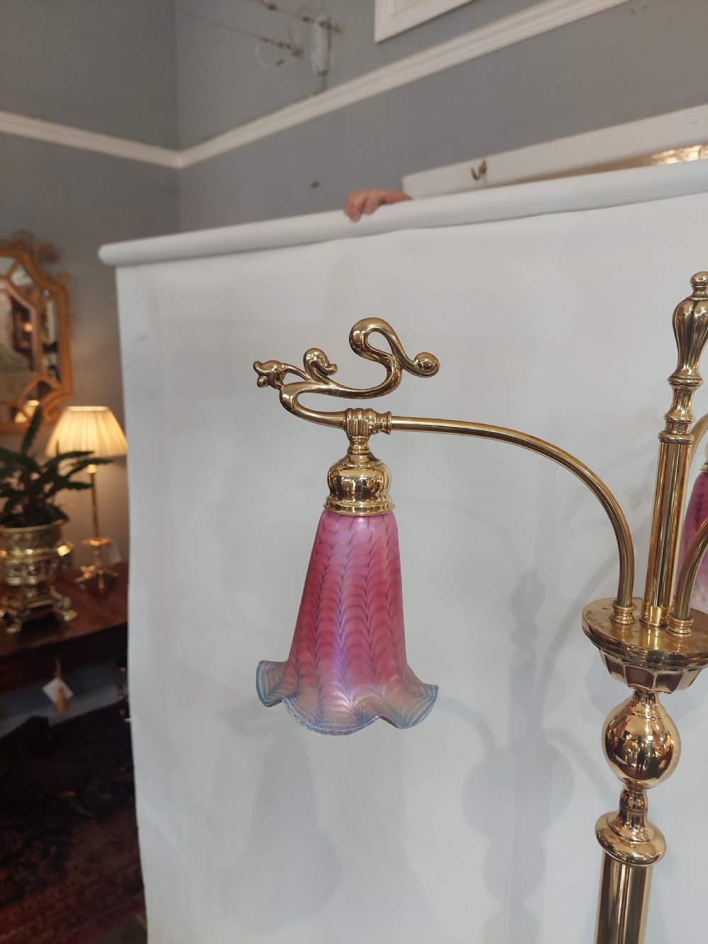 An Art Nouveau brass standard lamp with a slender central column, three curving arms holding frilled pink glass shades, and a tripod base. View III