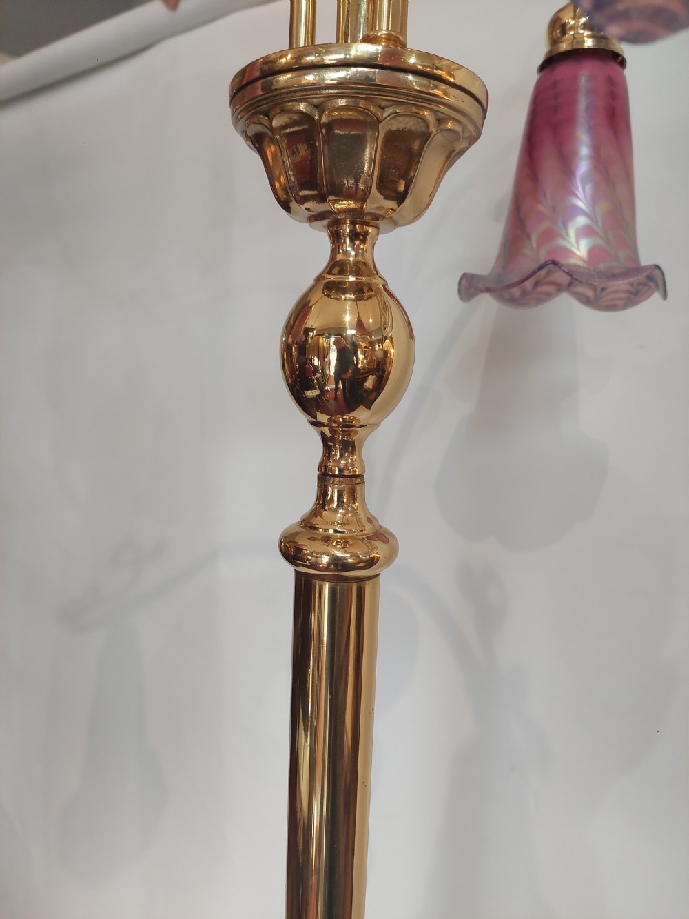 An Art Nouveau brass standard lamp with a slender central column, three curving arms holding frilled pink glass shades, and a tripod base. View VIII