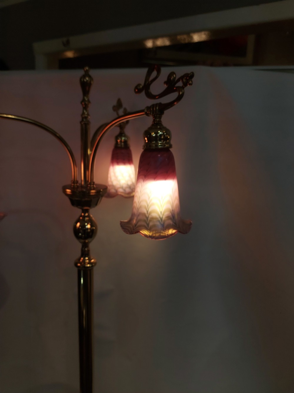 An Art Nouveau brass standard lamp with a slender central column, three curving arms holding frilled pink glass shades, and a tripod base. View XIV