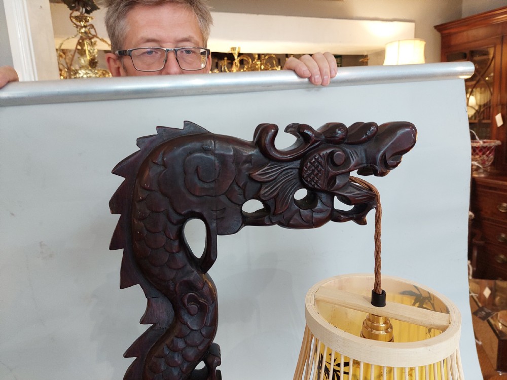 A late 19th-century dark carved hardwood lantern stand shaped like a dragon holding a suspended bamboo and paper cage lantern. View VI