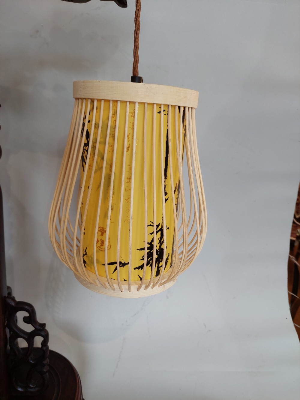 A late 19th-century dark carved hardwood lantern stand shaped like a dragon holding a suspended bamboo and paper cage lantern. View VII