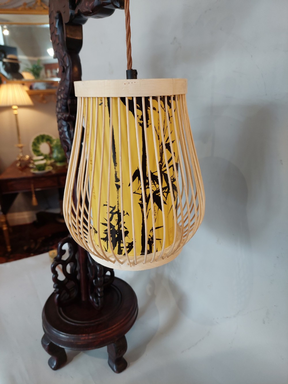 A late 19th-century dark carved hardwood lantern stand shaped like a dragon holding a suspended bamboo and paper cage lantern. View VIII
