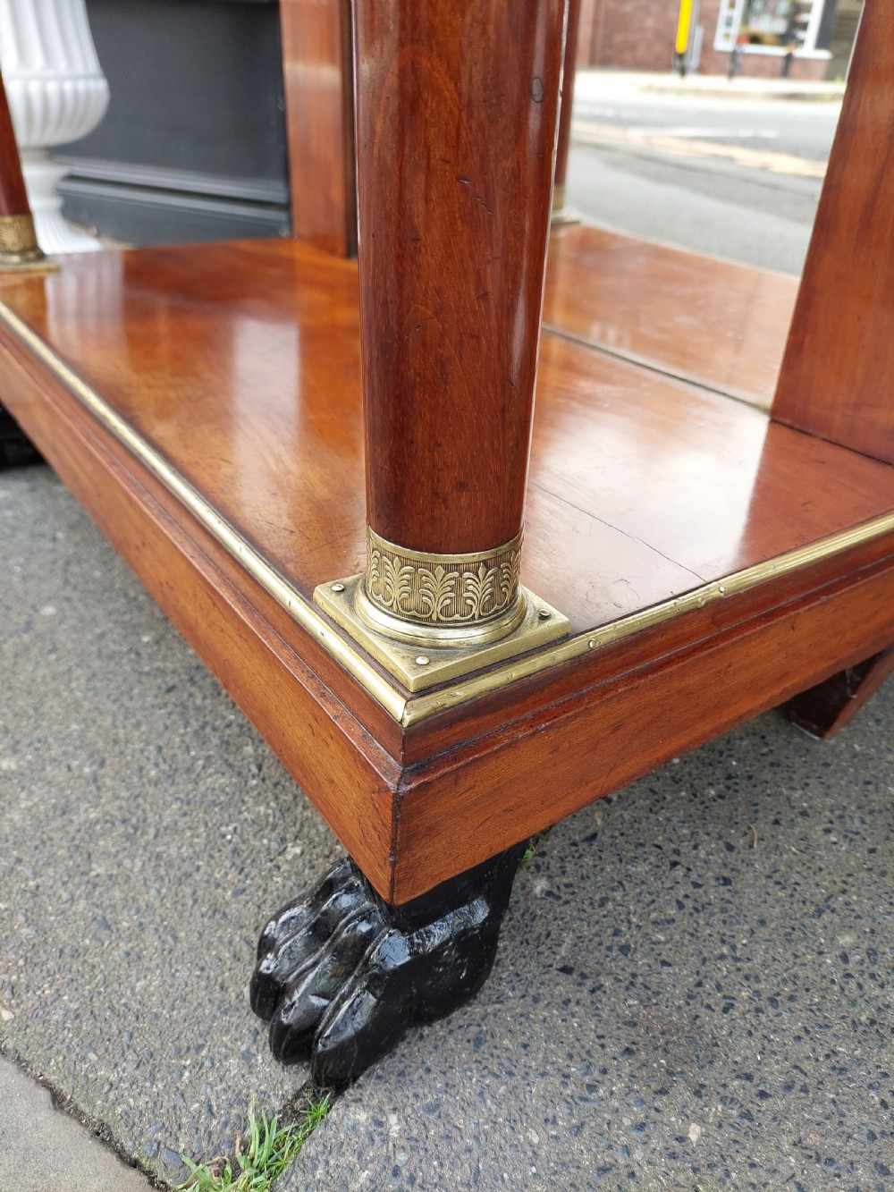 An early twentieth-century French Empire style console table crafted from mahogany with a grey-veined white marble top, columnar legs with gilt mounts, a mirrored back, and carved paw feet. View II