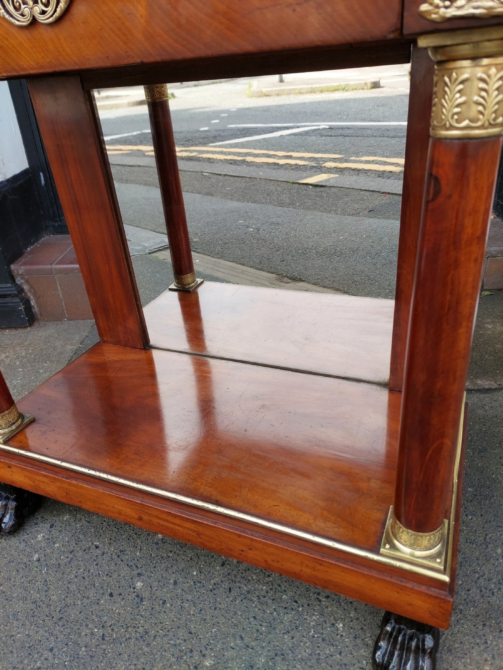An early twentieth-century French Empire style console table crafted from mahogany with a grey-veined white marble top, columnar legs with gilt mounts, a mirrored back, and carved paw feet. View IV