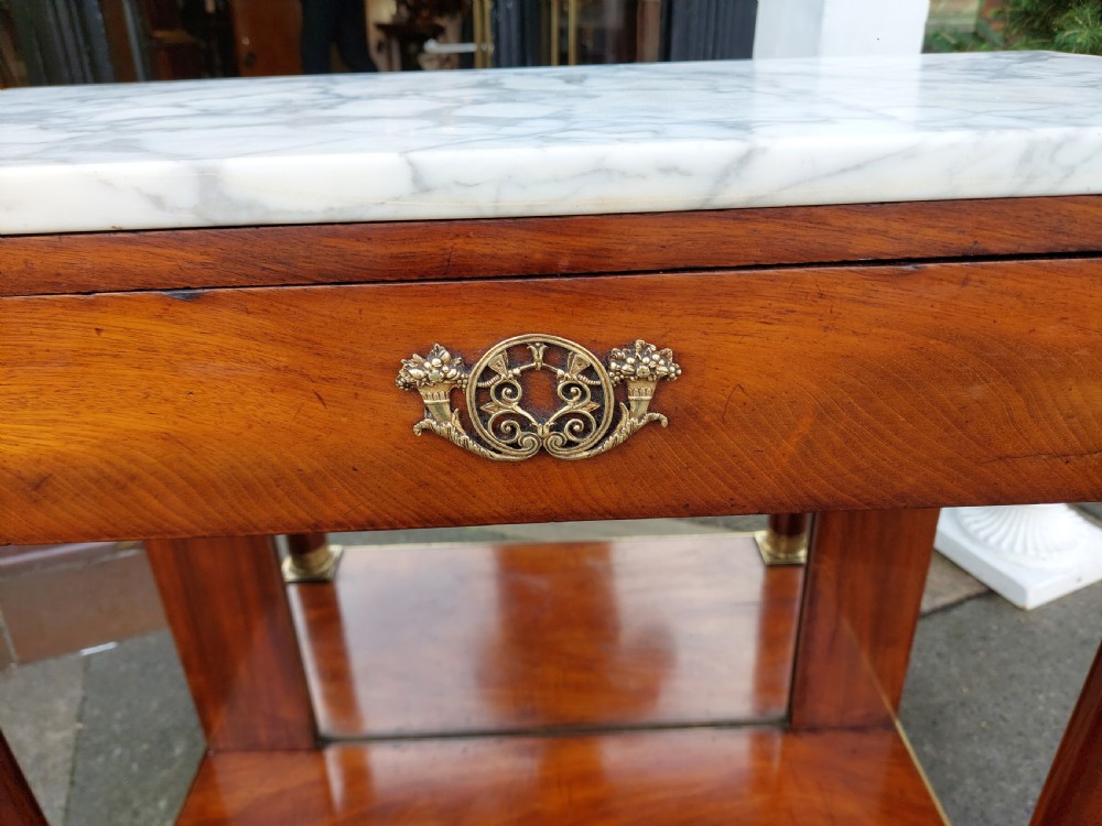 An early twentieth-century French Empire style console table crafted from mahogany with a grey-veined white marble top, columnar legs with gilt mounts, a mirrored back, and carved paw feet. View VI