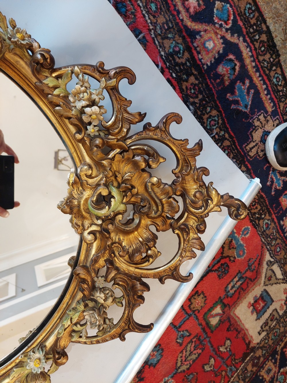 An early 20th-century Italianate giltwood wall mirror featuring an intricate carved crest, asymmetric Rococo scrolls, floral accents, and sculpted putti heads. View VII