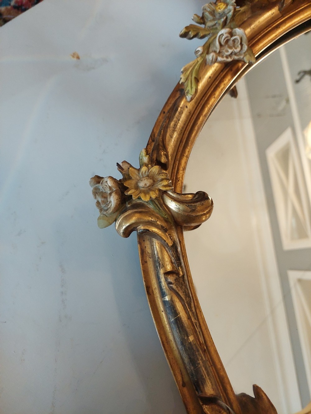 An early 20th-century Italianate giltwood wall mirror featuring an intricate carved crest, asymmetric Rococo scrolls, floral accents, and sculpted putti heads. View VIII