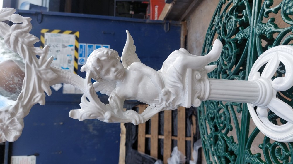 A white-painted cast iron tabletop mirror featuring cherub figures, floral garlands, and a central column pedestal. View II