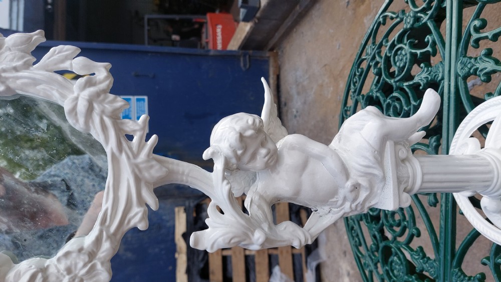 A white-painted cast iron tabletop mirror featuring cherub figures, floral garlands, and a central column pedestal. View III