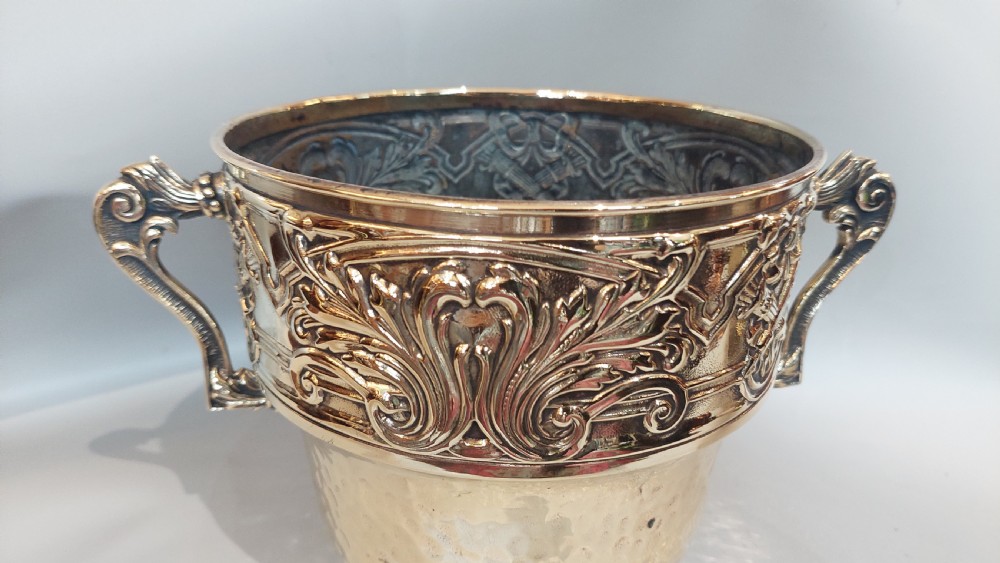 A late nineteenth-century French brass two-handled trophy vase with an embossed foliate frieze and a hammered base. View V