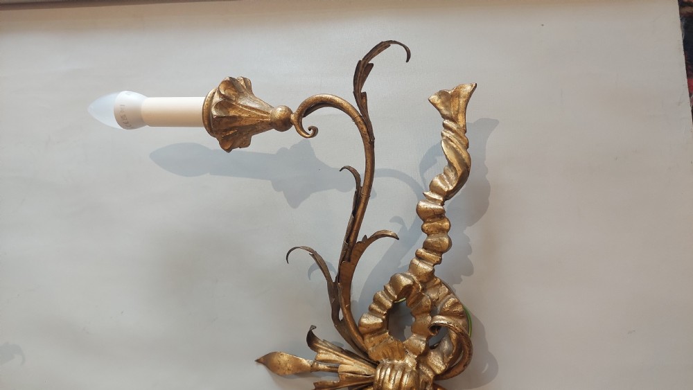 A pair of carved giltwood two-branch wall lights decorated with ribbon bows and foliate leaf scrollwork, holding two candle-style bulbs each. View III