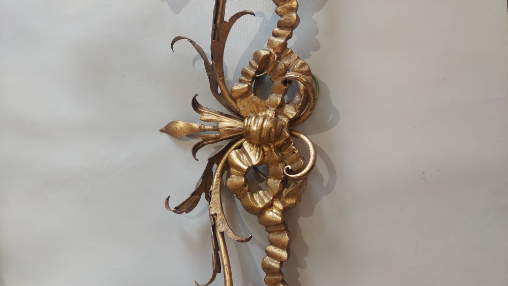 A pair of carved giltwood two-branch wall lights decorated with ribbon bows and foliate leaf scrollwork, holding two candle-style bulbs each. View IV