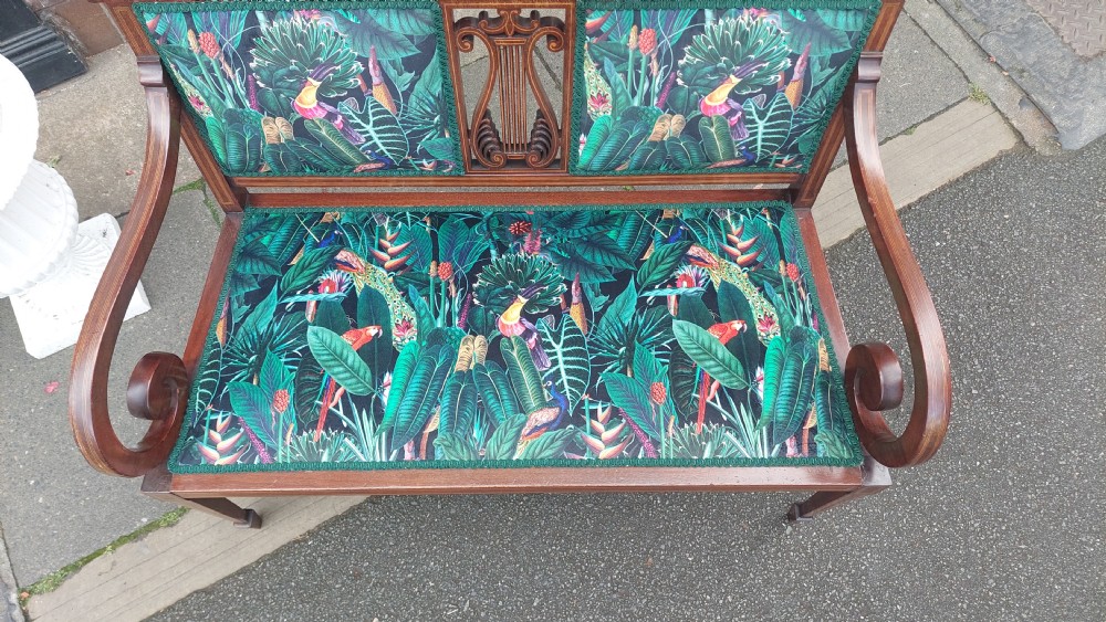 An Edwardian inlaid mahogany two-seater settee with swept scroll arms, a central lyre-shaped splat, and green botanical pattern upholstery. View III