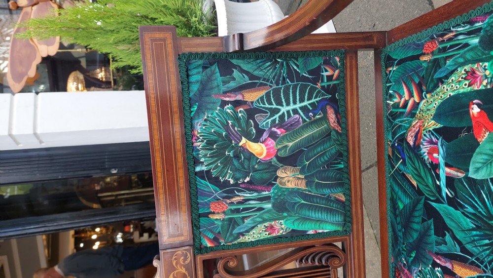 An Edwardian inlaid mahogany two-seater settee with swept scroll arms, a central lyre-shaped splat, and green botanical pattern upholstery. View V