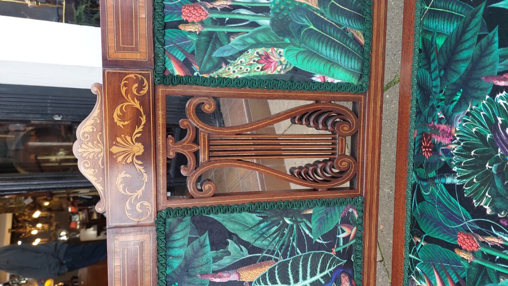 An Edwardian inlaid mahogany two-seater settee with swept scroll arms, a central lyre-shaped splat, and green botanical pattern upholstery. View VI