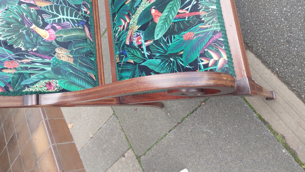 An Edwardian inlaid mahogany two-seater settee with swept scroll arms, a central lyre-shaped splat, and green botanical pattern upholstery. View VII