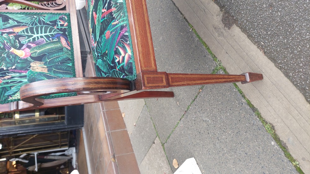 An Edwardian inlaid mahogany two-seater settee with swept scroll arms, a central lyre-shaped splat, and green botanical pattern upholstery. View VIII