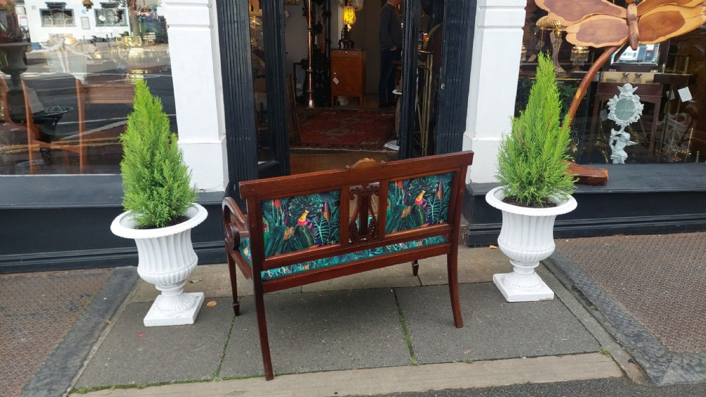 An Edwardian inlaid mahogany two-seater settee with swept scroll arms, a central lyre-shaped splat, and green botanical pattern upholstery. View XI