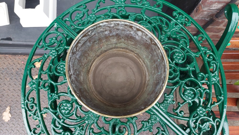 A tapered cylindrical brass planter featuring embossed Art Nouveau floral motifs above a textured hammered base. View III