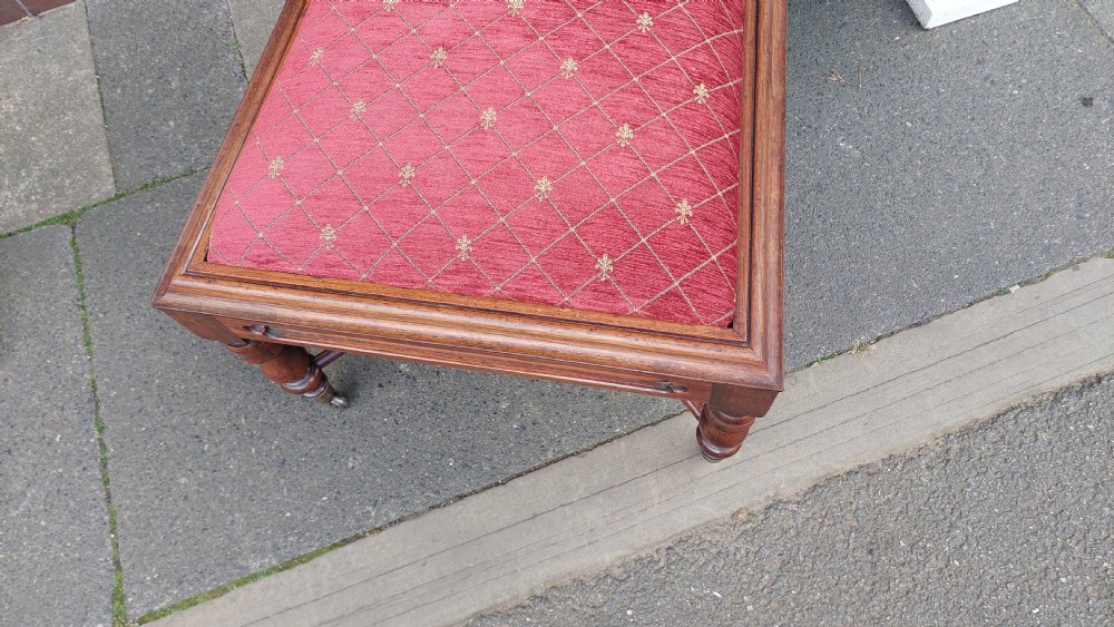An early Gothic Revival solid rosewood nursing chair featuring spiralled barley-twist uprights, carved cresting, red patterned upholstery, and brass castors. View IV