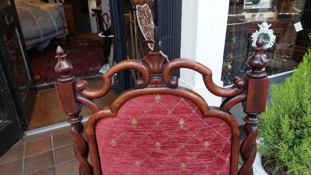 An early Gothic Revival solid rosewood nursing chair featuring spiralled barley-twist uprights, carved cresting, red patterned upholstery, and brass castors. View V