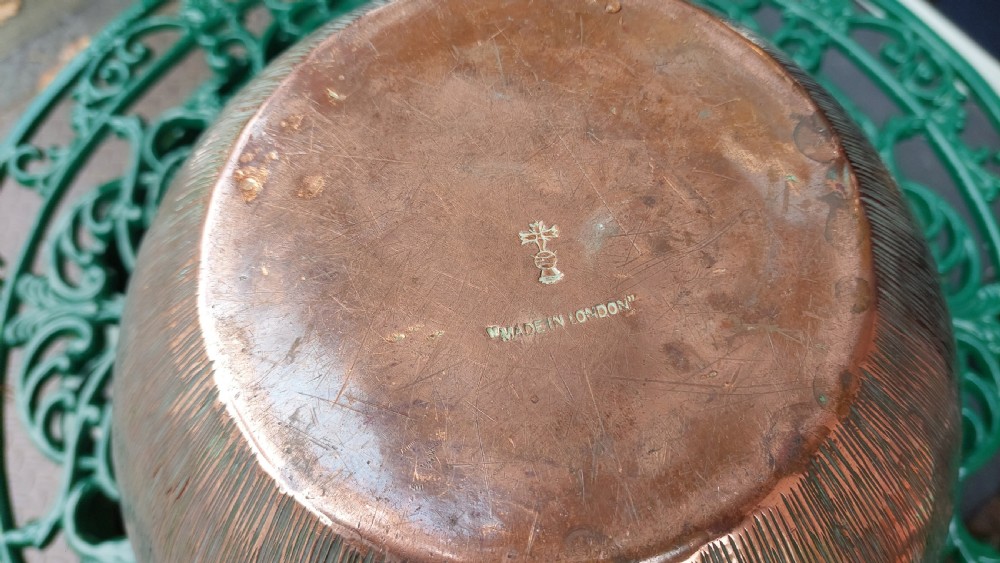 A round copper Arts and Crafts jardiniere featuring a textured hammered body and a crimped ruffled rim. View V