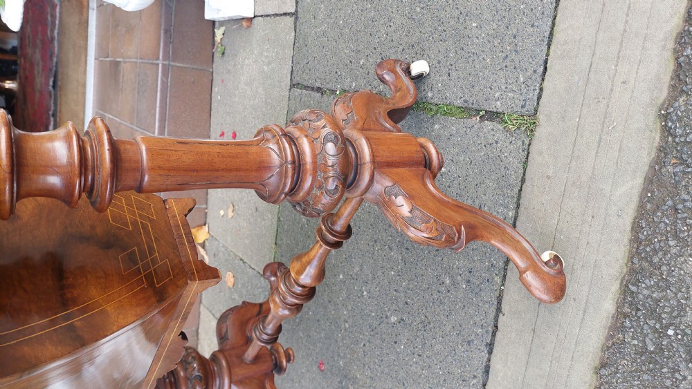 A nineteenth-century burr walnut games and work table featuring marquetry inlay, turned support columns, a lower work well, and carved legs on castors. View IV