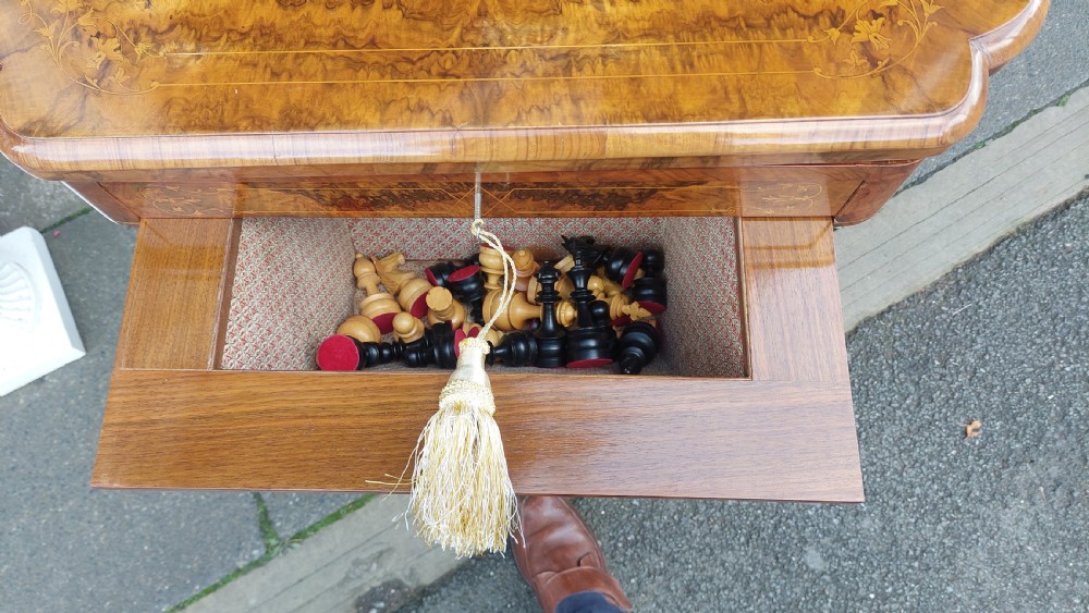 A nineteenth-century burr walnut games and work table featuring marquetry inlay, turned support columns, a lower work well, and carved legs on castors. View IX