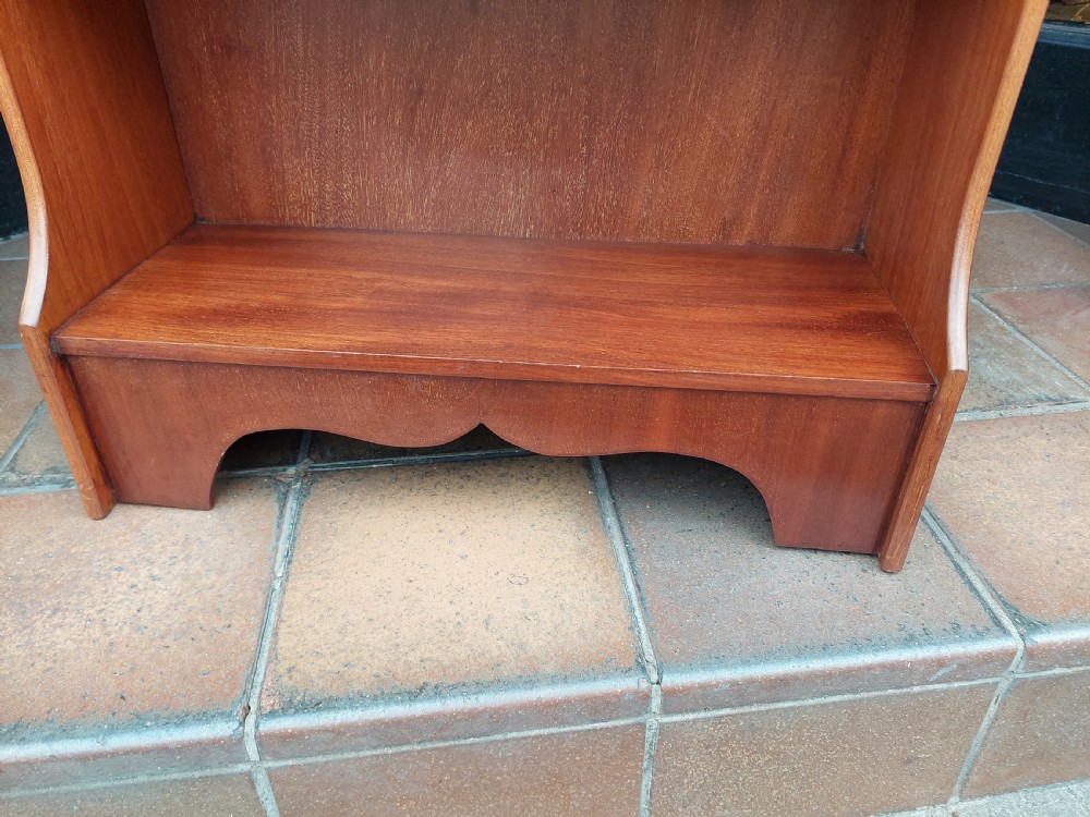 An Edwardian mahogany wall-hanging bookshelf featuring three open tiers, shaped side panels, an arched top cresting, and a polished warm brown finish. View III