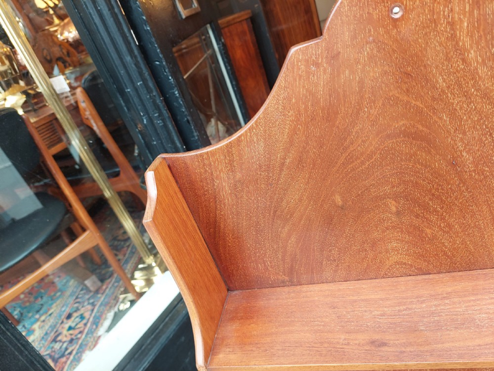 An Edwardian mahogany wall-hanging bookshelf featuring three open tiers, shaped side panels, an arched top cresting, and a polished warm brown finish. View V