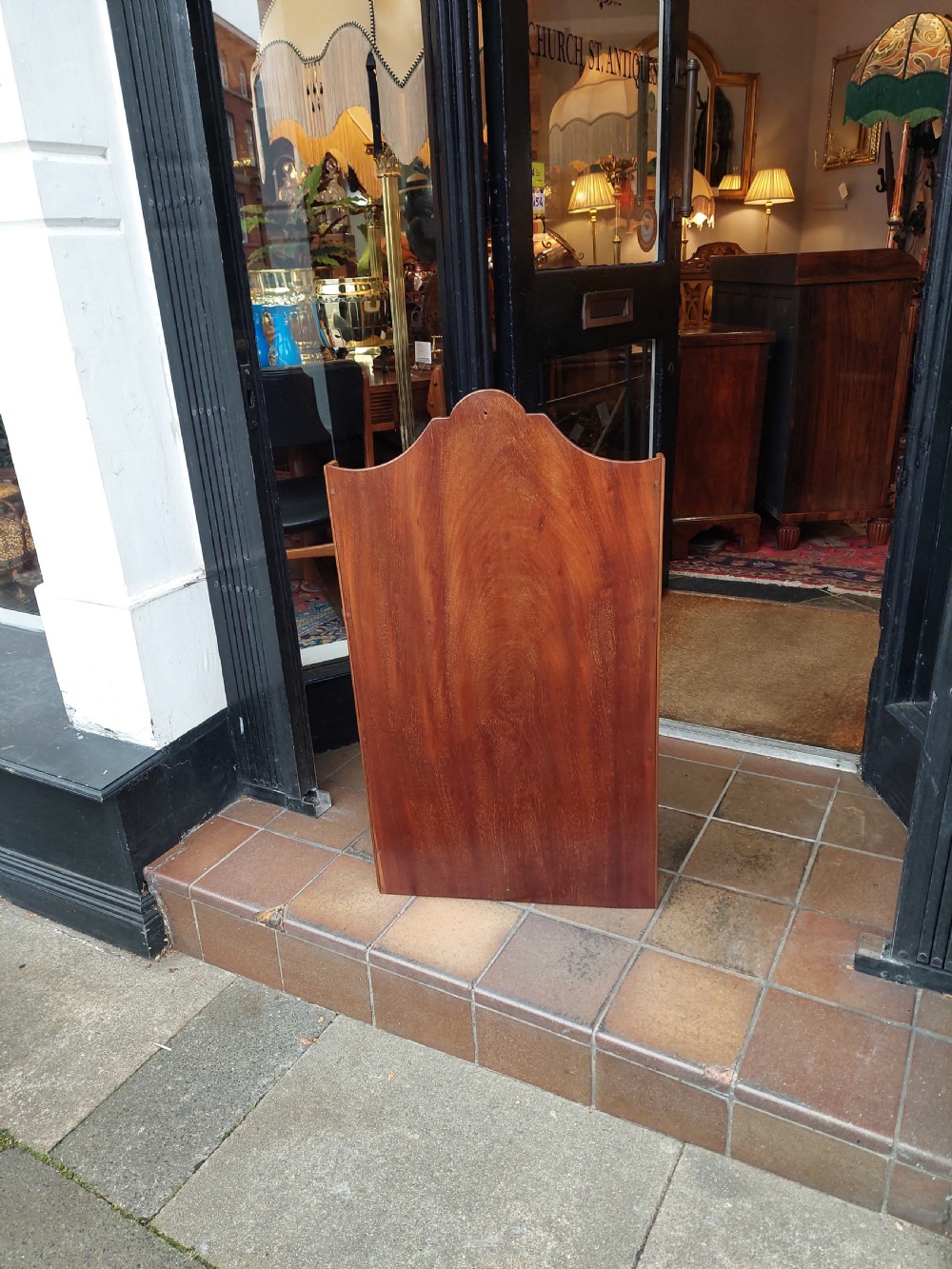 An Edwardian mahogany wall-hanging bookshelf featuring three open tiers, shaped side panels, an arched top cresting, and a polished warm brown finish. View VIII