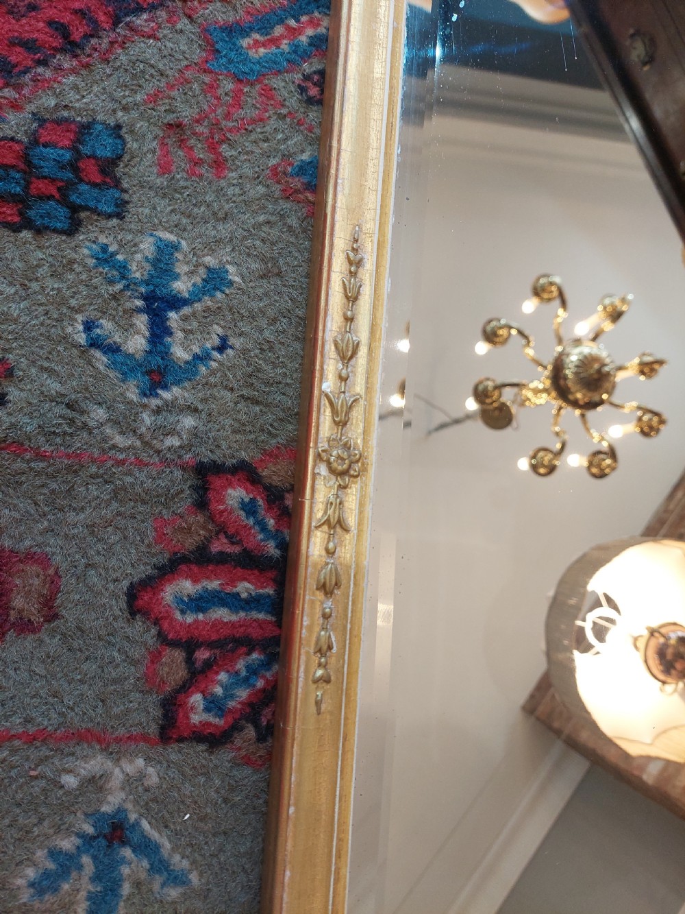 A 19th-century rectangular giltwood overmantel mirror with rounded top corners and subtle leaf moulding details along the gold frame. View IV
