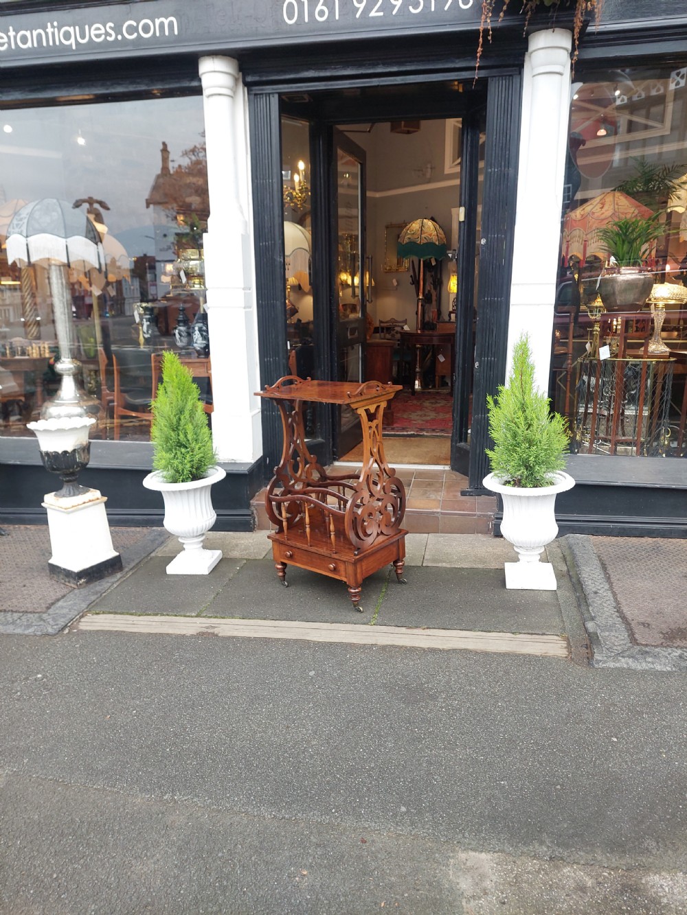 A Victorian rosewood Canterbury whatnot featuring a top shelf supported by pierced fretwork side panels, slatted sheet music partitions, a lower drawer, and turned legs with brass castors. View VII