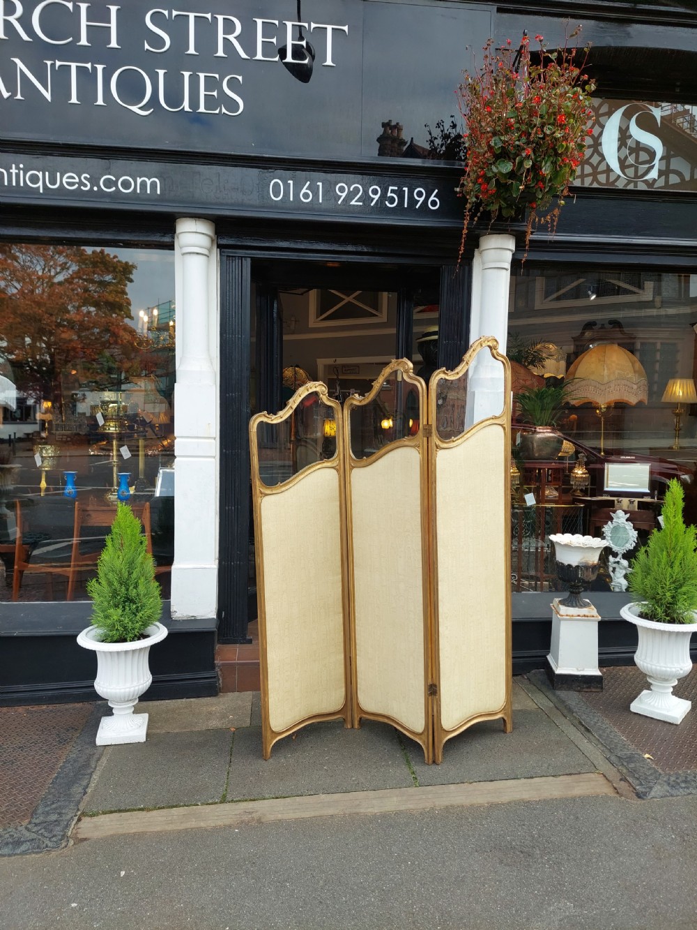 A mid-19th century three-panel giltwood vanity screen featuring carved Rococo cresting, clear glass top panels, and cream upholstered lower panels. View II