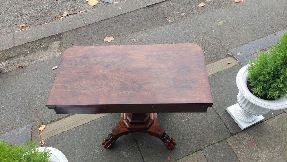 A 19th-century William IV rosewood fold-over card table supported on a central tapered pedestal and a quadruped base with carved scroll feet. View IV