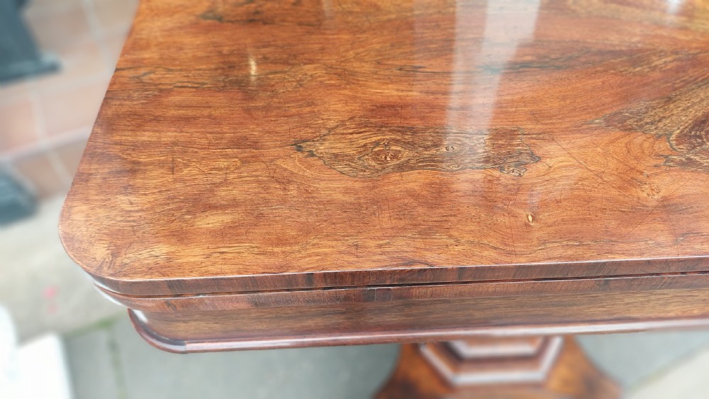 A 19th-century William IV rosewood fold-over card table supported on a central tapered pedestal and a quadruped base with carved scroll feet. View VI