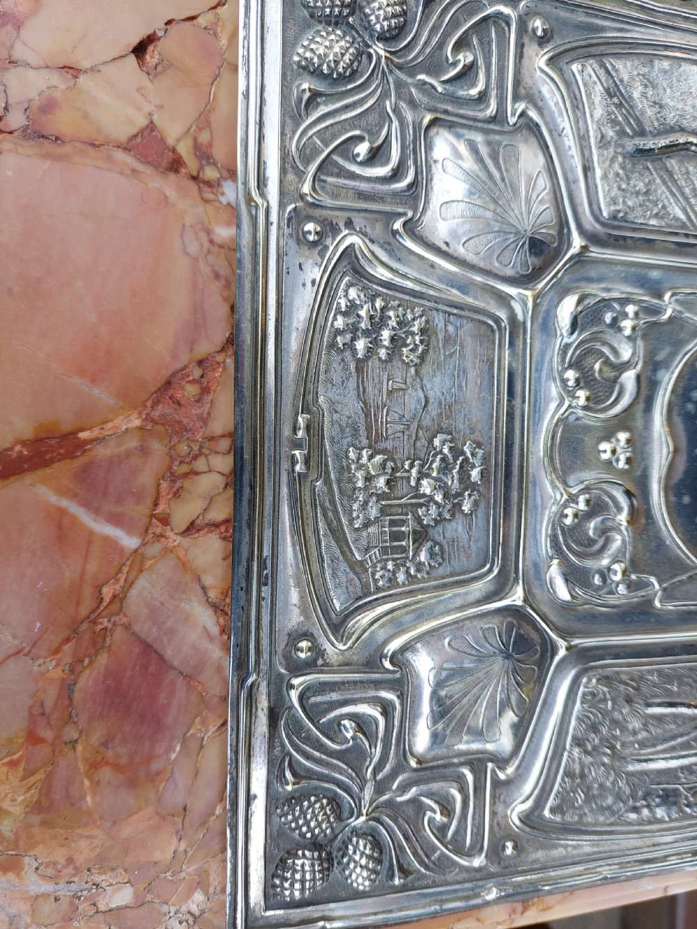 A rectangular silver-plated Art Nouveau blotter folio featuring relief embossed panels of trees, landscapes, pinecone motifs, and a central polished cartouche. View VIII