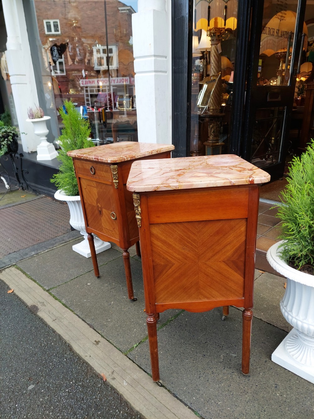 A pair of late nineteenth-century French walnut bedside cabinets featuring pink veined marble tops, marquetry floral inlay on the doors, brass mounts, and slender turned legs. View II