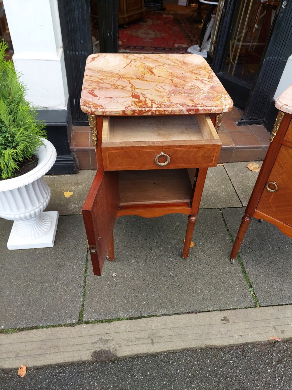 A pair of late nineteenth-century French walnut bedside cabinets featuring pink veined marble tops, marquetry floral inlay on the doors, brass mounts, and slender turned legs. View VII