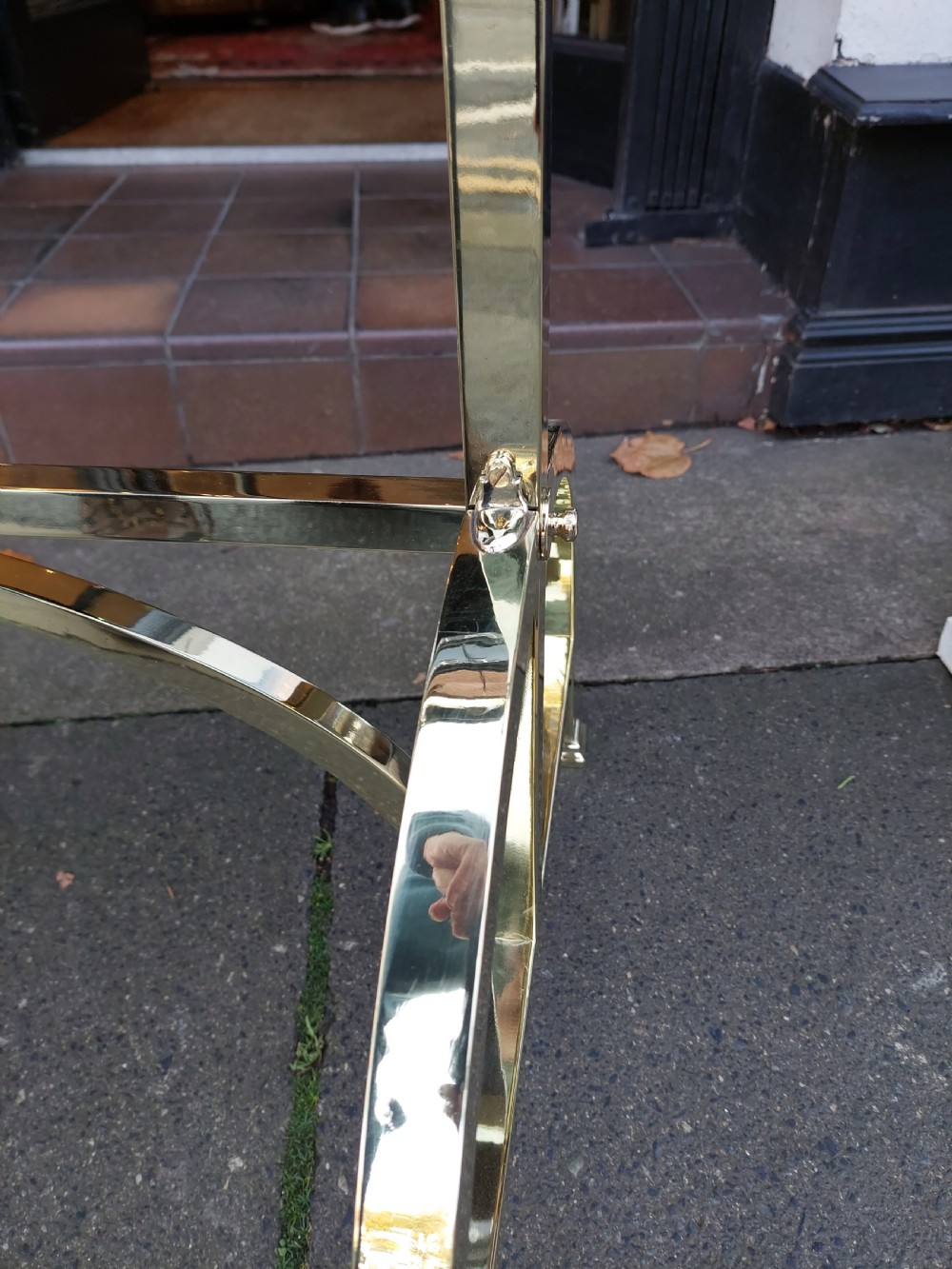 An Edwardian brass cheval mirror featuring an oval bevelled glass frame with decorative cresting and side candle sconces supported on a slender standing base. View VII