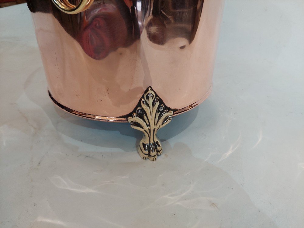 A cylindrical polished copper coal bucket featuring a fitted lid with a brass finial, side ring handles attached to lion mask mounts, and four detailed brass paw feet. View VI